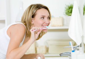 Фотография девушки у зеркала, чистящей зубы